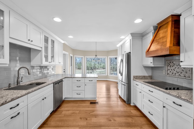 kitchen featuring stainless steel appliances, a peninsula, a sink, white cabinetry, and custom range hood