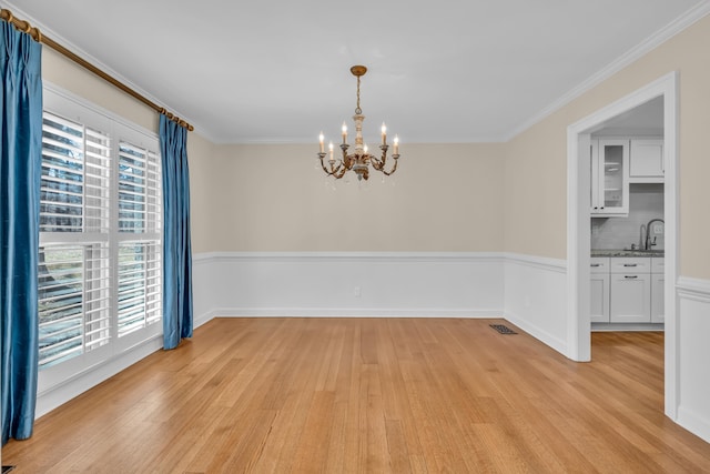 unfurnished dining area featuring ornamental molding, light wood-type flooring, and a sink