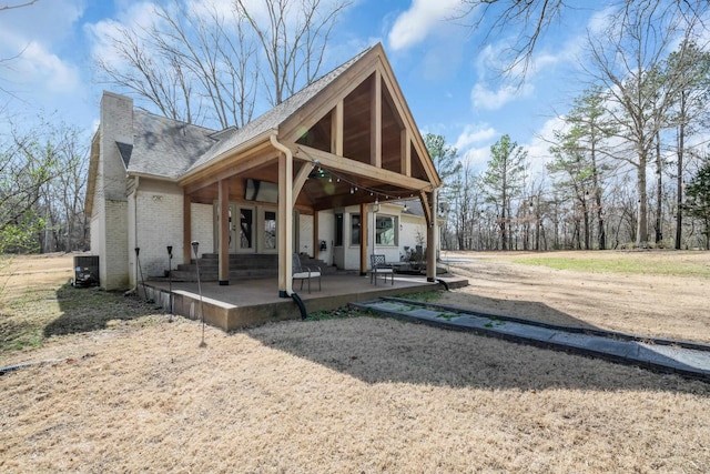 back of property featuring a shingled roof, a patio, french doors, central air condition unit, and brick siding