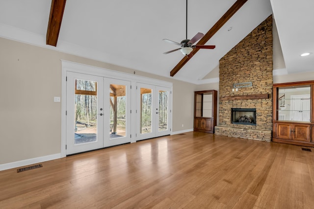 unfurnished living room with light wood-style floors, french doors, visible vents, and a stone fireplace