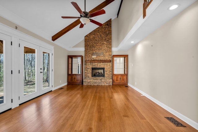 unfurnished living room featuring a stone fireplace, light wood-style flooring, visible vents, and baseboards