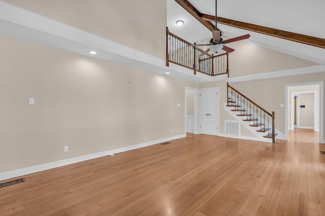 unfurnished living room with stairs, light wood finished floors, beam ceiling, and visible vents