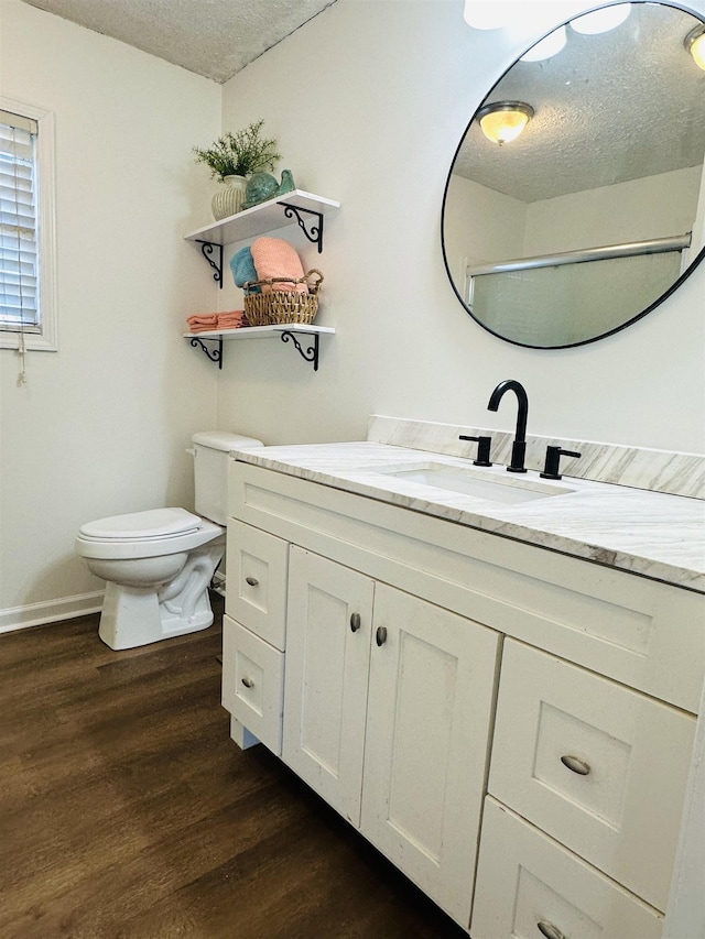 bathroom with a textured ceiling, toilet, wood finished floors, and vanity