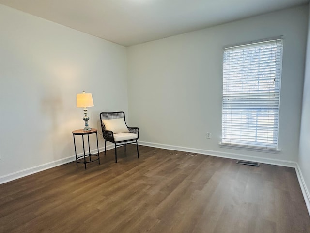 living area featuring visible vents, dark wood finished floors, and baseboards