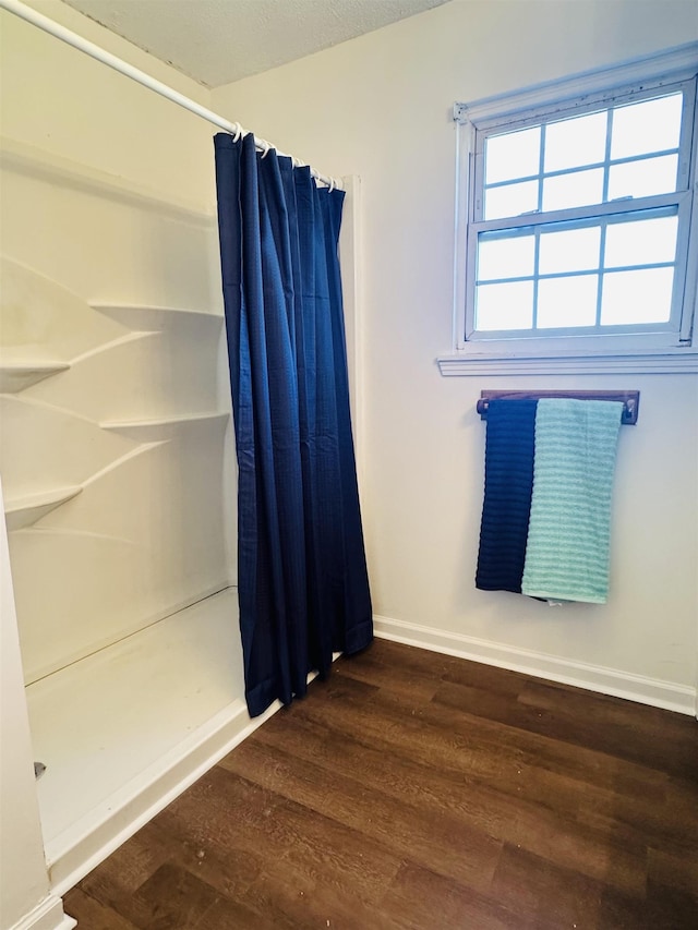 interior space featuring curtained shower, baseboards, and wood finished floors