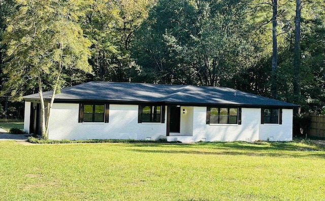 ranch-style home with a front yard, fence, a wooded view, and brick siding