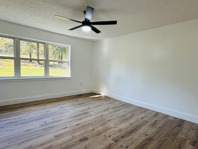 spare room with ceiling fan, a textured ceiling, baseboards, and wood finished floors