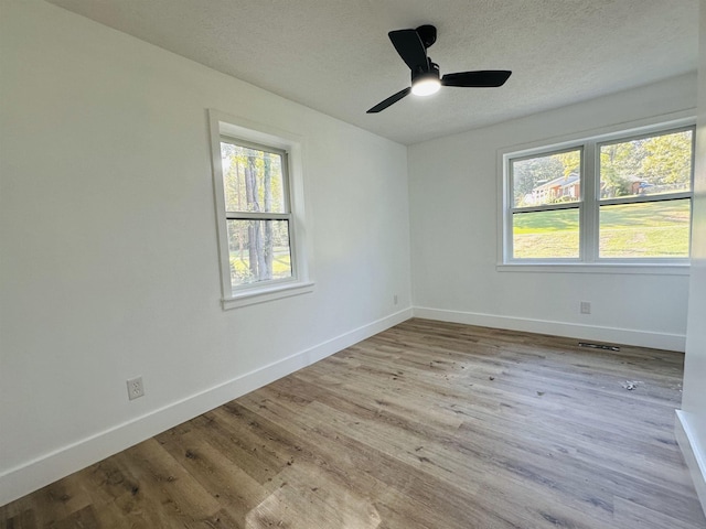 spare room with visible vents, a textured ceiling, baseboards, and wood finished floors