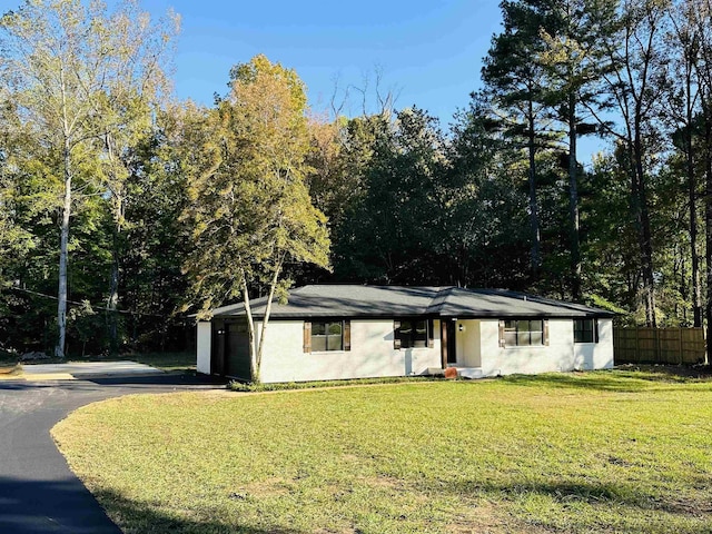 ranch-style home featuring an attached garage, driveway, a front lawn, and fence