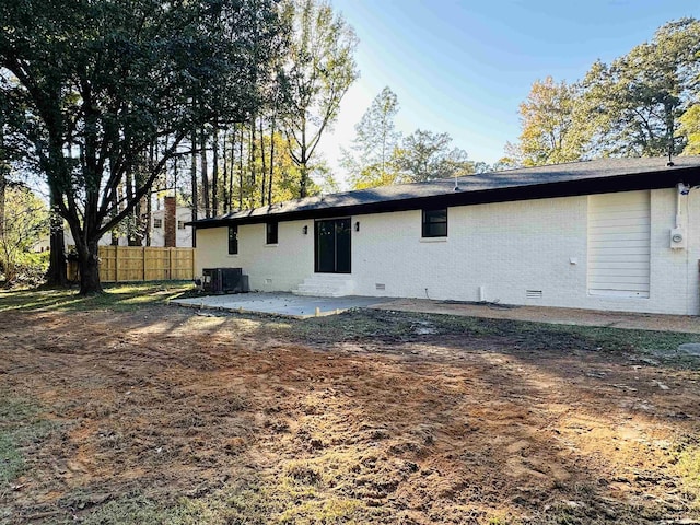 back of property with crawl space, brick siding, fence, and central air condition unit