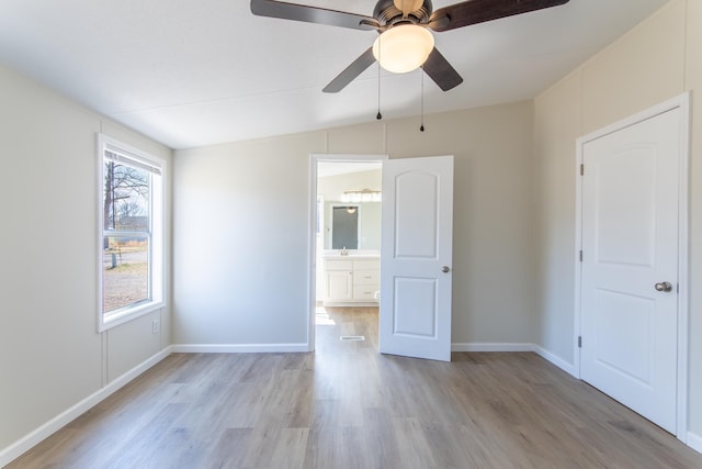 unfurnished bedroom with light wood-style floors, ceiling fan, baseboards, and connected bathroom