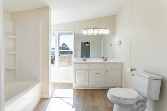 full bath featuring double vanity, a sink, toilet, and wood finished floors