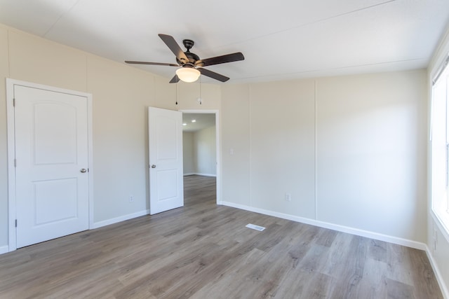 spare room with a ceiling fan, a wealth of natural light, and light wood finished floors