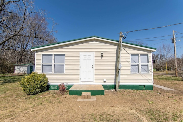 exterior space featuring crawl space, a storage unit, a front lawn, and an outdoor structure