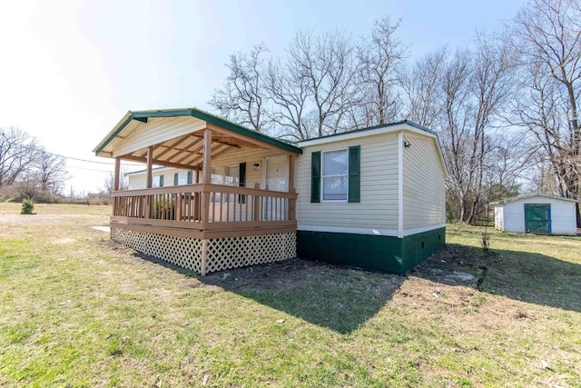 back of property featuring a deck, an outdoor structure, and a yard