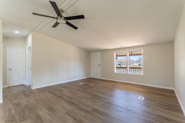 empty room with lofted ceiling, a ceiling fan, baseboards, and wood finished floors