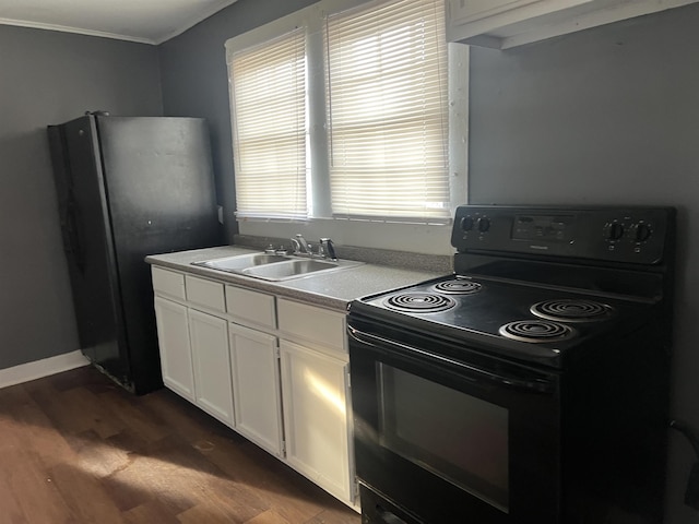 kitchen with black electric range oven, dark wood-type flooring, freestanding refrigerator, white cabinetry, and a sink