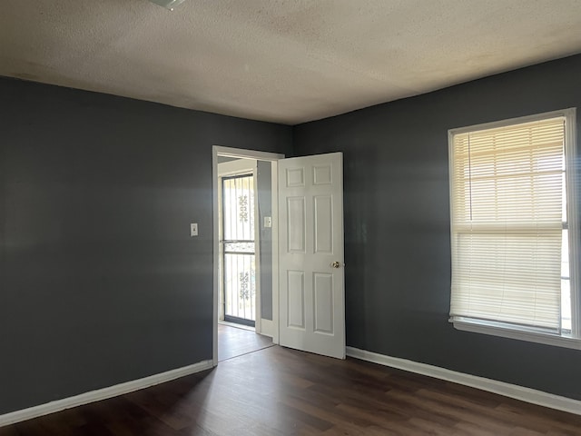 spare room with dark wood-style floors, baseboards, and a textured ceiling