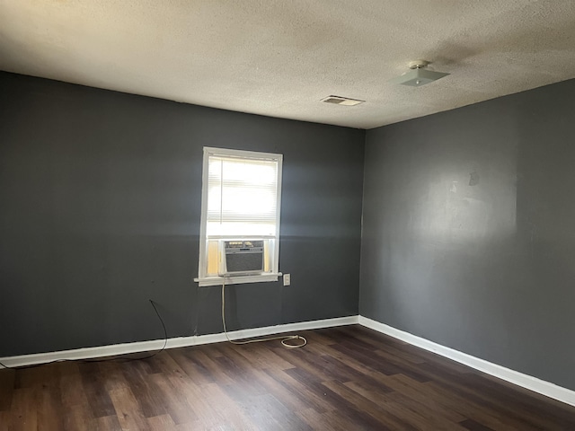 unfurnished room with dark wood-type flooring, visible vents, a textured ceiling, and baseboards