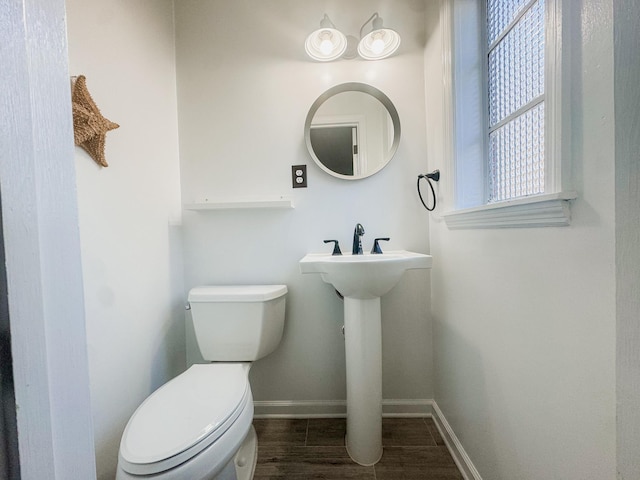 half bath featuring toilet, baseboards, and wood finished floors