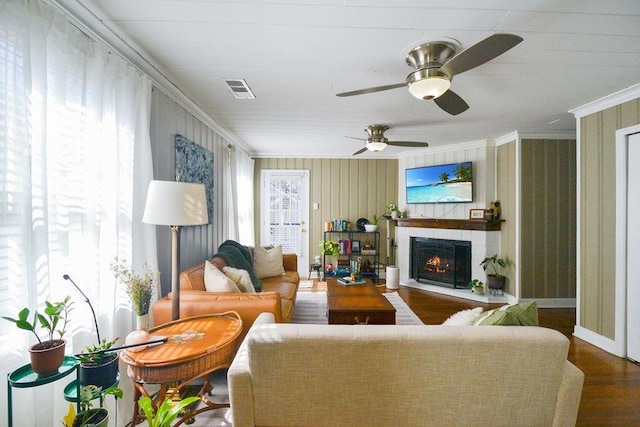 living area with a wealth of natural light, visible vents, crown molding, and wood finished floors