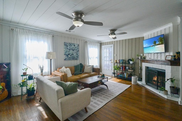 living area featuring a healthy amount of sunlight, visible vents, ornamental molding, and wood finished floors