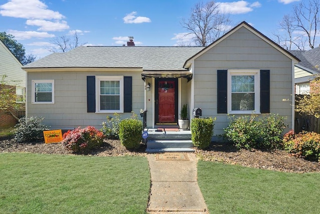 bungalow-style home with a shingled roof and a front lawn