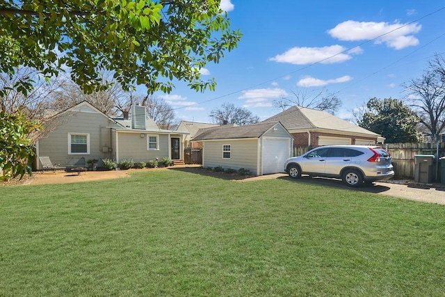 view of front of property with a garage, an outdoor structure, fence, a chimney, and a front yard