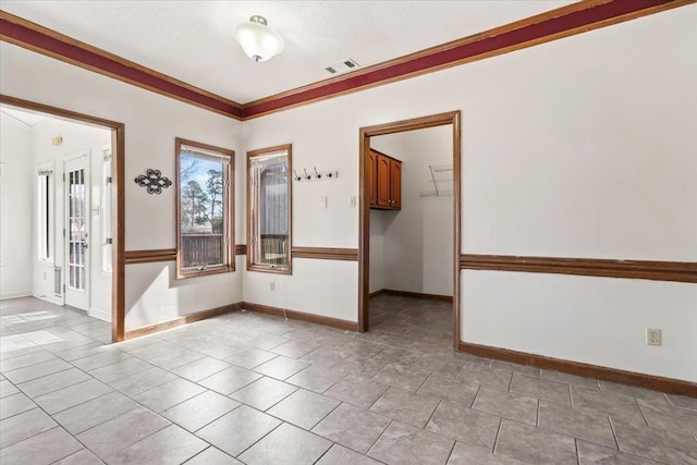 spare room with visible vents, crown molding, and baseboards