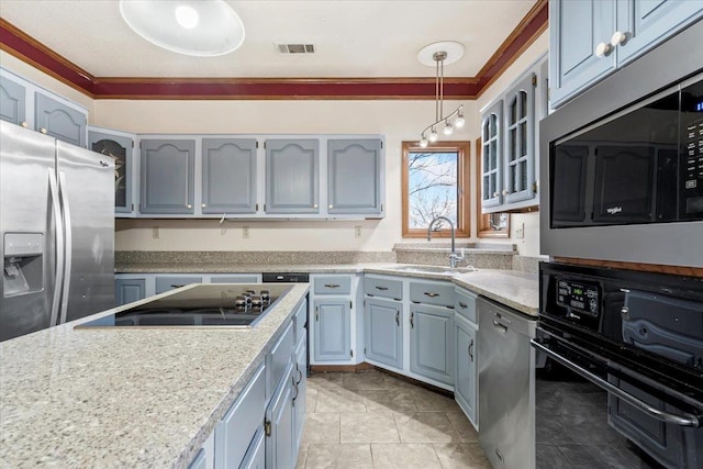 kitchen featuring ornamental molding, light countertops, black appliances, pendant lighting, and a sink