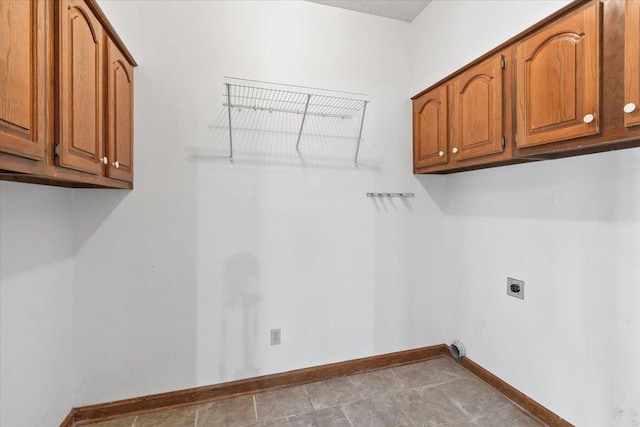 laundry area featuring hookup for an electric dryer, cabinet space, and baseboards