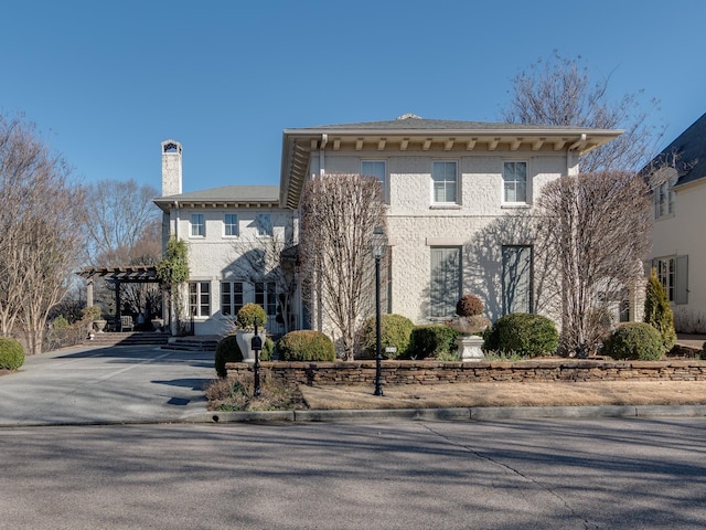 italianate house featuring a carport, a chimney, driveway, and a pergola