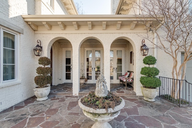 doorway to property with french doors, a patio area, and brick siding