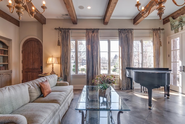 living area featuring a wealth of natural light, visible vents, a notable chandelier, and baseboards