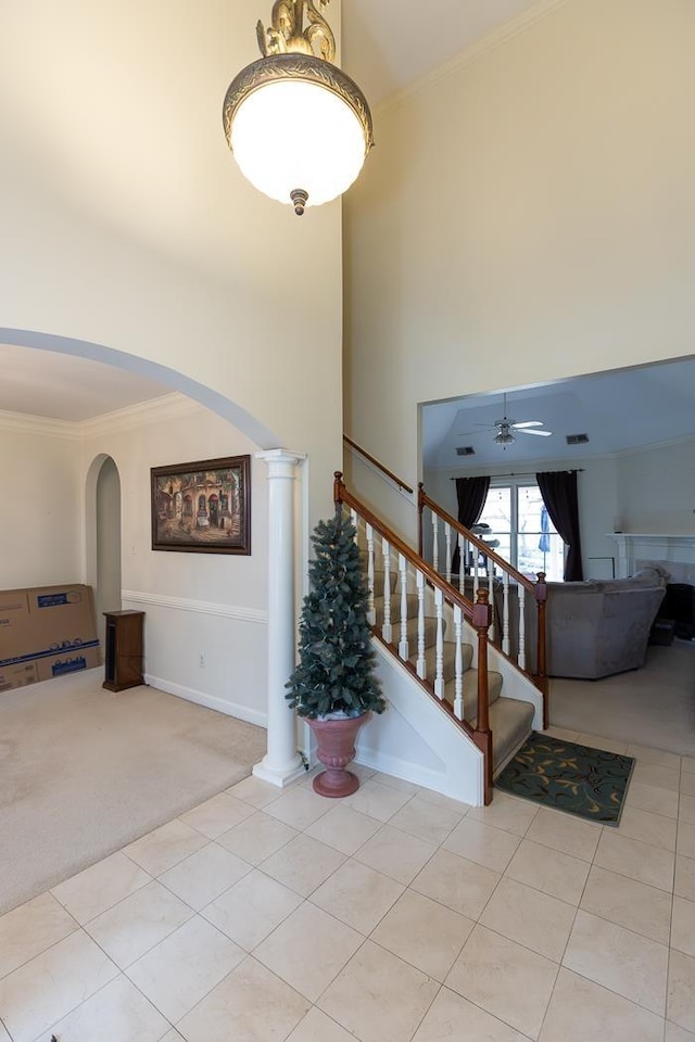 interior space featuring carpet floors, ornate columns, ornamental molding, and a ceiling fan