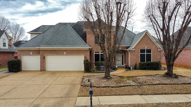 traditional-style house featuring driveway, brick siding, roof with shingles, and an attached garage