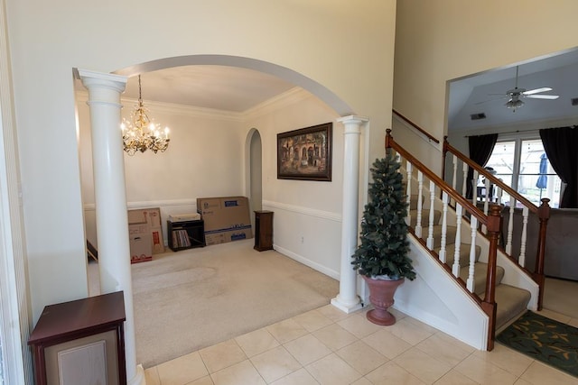 carpeted foyer entrance with decorative columns, ceiling fan, ornamental molding, tile patterned flooring, and stairs