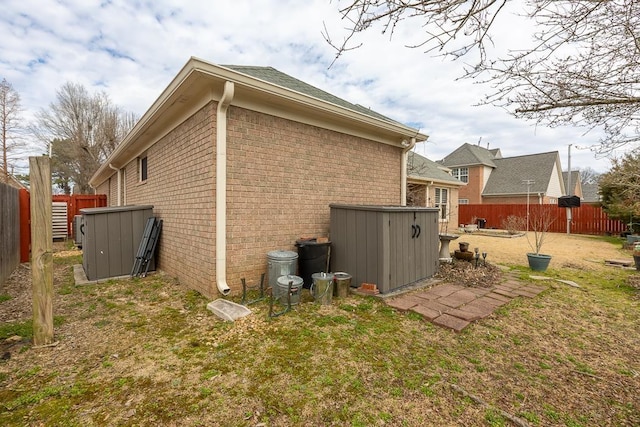 view of side of property with a yard, a fenced backyard, and brick siding