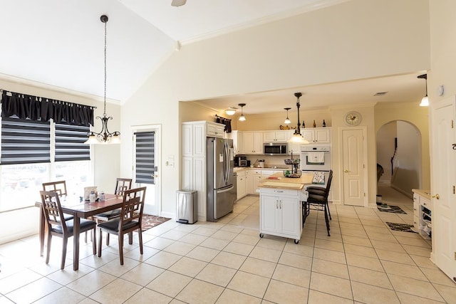 kitchen with light tile patterned floors, appliances with stainless steel finishes, a breakfast bar, crown molding, and white cabinetry