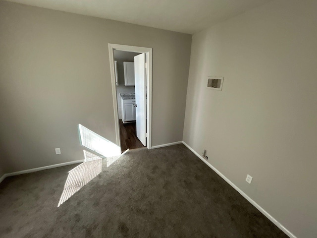 empty room with dark carpet and baseboards