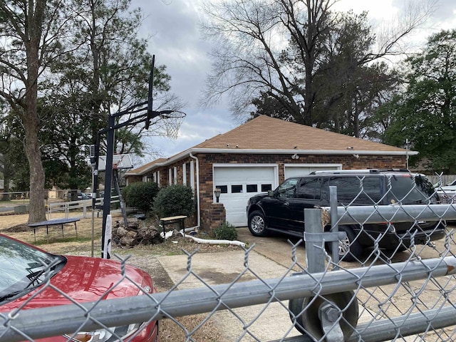 view of property exterior with a garage, roof with shingles, a trampoline, an outdoor structure, and brick siding