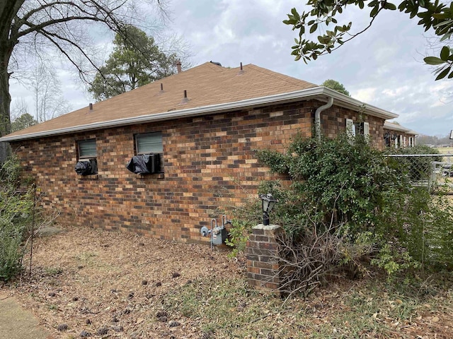 view of home's exterior featuring brick siding and roof with shingles