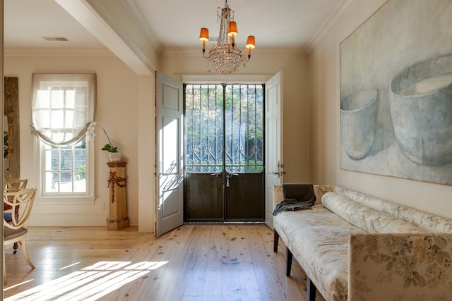 doorway to outside featuring ornamental molding, a chandelier, visible vents, and light wood finished floors