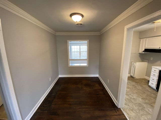 hallway featuring ornamental molding, wood finished floors, visible vents, and baseboards