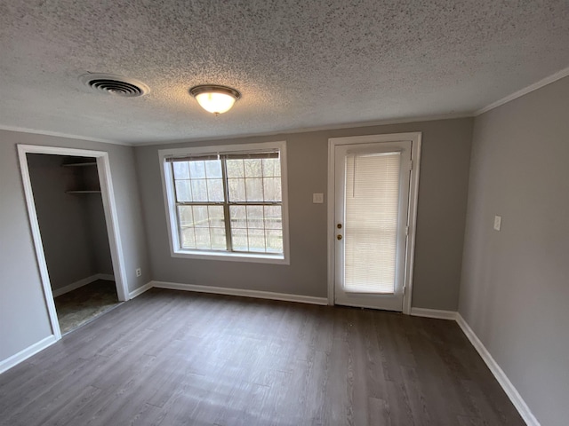 interior space featuring crown molding, dark wood finished floors, visible vents, a textured ceiling, and baseboards