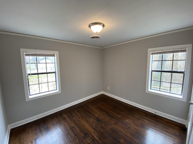 unfurnished room featuring dark wood-type flooring, visible vents, crown molding, and baseboards