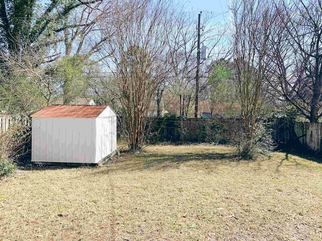 view of yard with a storage shed, an outbuilding, and a fenced backyard