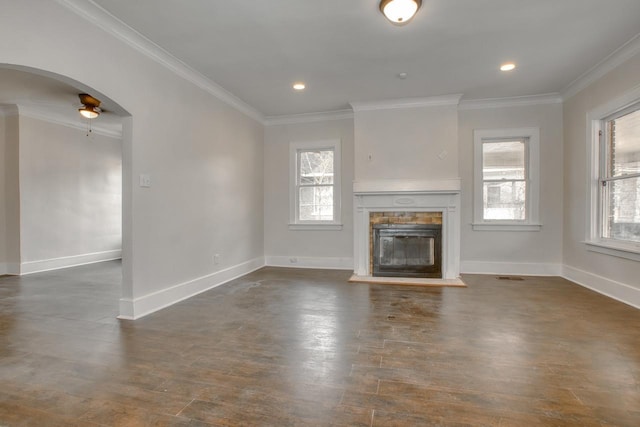 unfurnished living room featuring baseboards, arched walkways, a glass covered fireplace, ornamental molding, and dark wood-style flooring