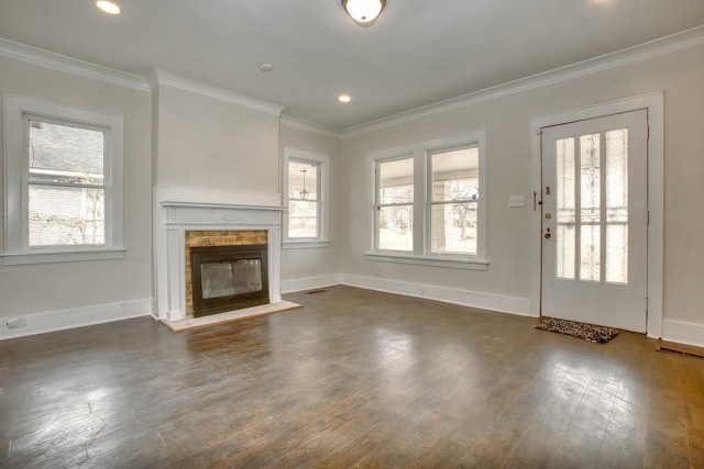 unfurnished living room featuring dark wood-style floors, visible vents, ornamental molding, a glass covered fireplace, and baseboards