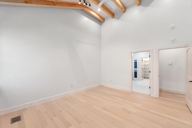 empty room featuring light wood finished floors, beam ceiling, visible vents, and baseboards